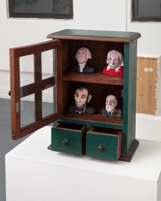 Bette Blank , The Fathers , 2019. Painted polymer clay in antique cabinet. 15 x 12 1/2 x 3 3/4 inches.