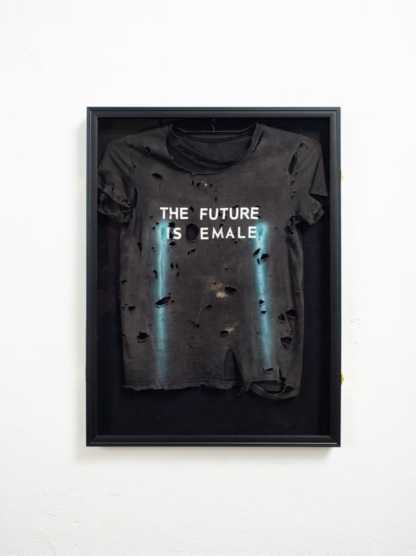 Louis Osmosis ,  Jogger #2 (THE FUTURE IS EMALE) , 2022. Distressed graphic tee, jersey display frame, airbrushed acrylic. 32 x 23.5 x 2 inches.