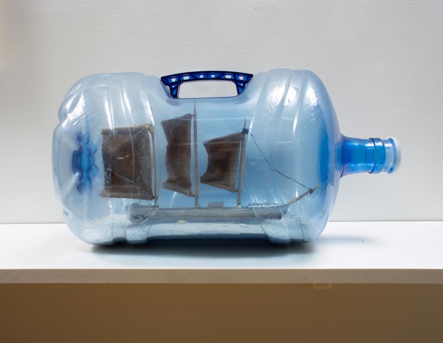 Louis Osmosis ,   Ship in a Bottle (Wreck) , 2022. Five-gallon water bottle, pine, rust-dyed canvas, acrylic paint, cyanoacrylate, waxed thread, cement, screws. 19 x 12 x 11 inches.